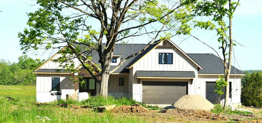 A new house partway through construction, with white board-and-batten siding on the walls